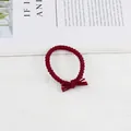 Detail of burgundy braided elastic hair tie with a minimalist knot on a white surface - Burgundy