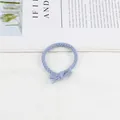 Detailed view of light blue braided hair tie with elegant decorative bow knot texture - Blue