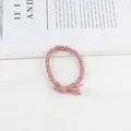 Pink braided hair tie with a small bow knot detail on a white textured background - Pink