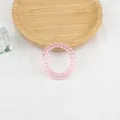 Dettaglio dell'elastico a spirale rosa pallido su vassoio in legno e trama bianca - Rosa chiaro