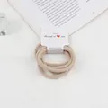 Set of 5 elastic hair ties in nude and beige tones on a white textured background - Beige