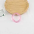Dettaglio di un elastico a spirale rosa in resina traslucida su un vassoio di legno - Rosa