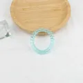 Detailaufnahme eines hellblauen Spiral-Haargummis auf weißem Stoff mit einem Holztablett - Hellblau