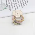 Detailopname van pastelkleurige haarelastiekjes met strikjes op een kattenkaart - Lente Kleuren