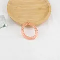 Macro di un elastico per capelli a spirale arancione-rosa su un vassoio di legno minimale - Arancione