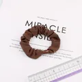 Detail of a brown pleated silk scrunchie with a matching plastic buckle fastener - Brown
