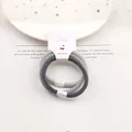 Detail von hochelastischen Haargummis mit irisierenden Perlen auf weißem Display - Grau