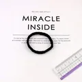 Detail of a thick black elastic hair tie with spiral texture and matte plastic buckle - Black