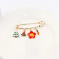 Détail d'une broche épingle dorée avec breloques émaillées de Noël sur une assiette blanche - Design No.5