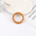 Detail of orange spiral hair tie with white heart pattern on a decorative tray - Turmeric