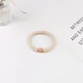 Détail macro d'un chouchou beige avec perle en strass or rose et texture tressée - Beige