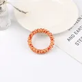 Close-up of spiral phone cord hair tie in light orange with red heart patterns - Orange Red