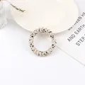 Detailed view of cream spiral hair tie with black heart patterns in a lifestyle setting - White