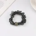 Detail of dark grey mesh scrunchie with sparkling rhinestone ball charm on white desk - Gray