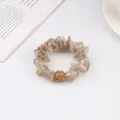 Close-up of champagne mesh scrunchie with sparkling rhinestone ball and textured fabric - Light Coffee