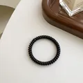 Elastisches schwarzes Spiral-Haargummi für Damen auf einem dekorativen Tablett - Schwarz