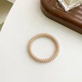 Elastisches beiges Spiral-Haargummi für Damen auf minimalistischer weißer Fläche - Hautfarben