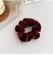 Detailed texture of burgundy velvet scrunchie on a cozy knitted background decor - Burgundy