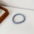 Elastic Morandi blue braided hair tie with a smooth oval decorative bead on a white surface - Blue