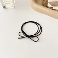 Minimalistisches schwarzes Haargummi mit goldenen Metallzylindern und Schleifenknoten - Schwarz