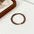 Elastic deep brown hair tie with rose gold metallic buckle on a clean white background - Brown