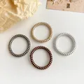 Metallic spiral hair ties in black, gold, bronze and silver on minimalist background - Multicolor