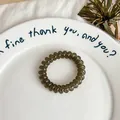 Elastic translucent grey spiral hair tie in a minimalist ceramic dish setting - Olive Green