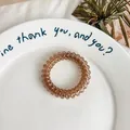Translucent amber brown spiral telephone wire hair tie on a white ceramic tray - Grey Coffee