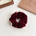 Burgundy velvet scrunchie with rhinestones and cream trim in a cozy setting - Burgundy