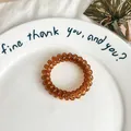 Single translucent brown spiral hair tie with high elasticity in a ceramic plate - Medium Coffee