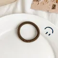 Brown high-elasticity spiral telephone wire hair tie on white ceramic plate - Matte Dark Brown
