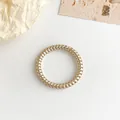 Coletero en espiral color oro champán metalizado sobre un fondo minimalista y elegante - Champán