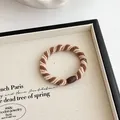 Elastisch gevlochten haarelastiekje in beige en koffiebruin met een bruine hars sluiting - Bruin