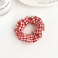 Red and white checkered fabric scrunchie in plaid pattern for stylish ponytails - Red