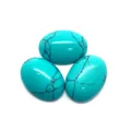 Gros plan de trois cabochons de turquoise ovales avec matrice noire sur fond blanc - 6X8mm / Turquoise Bleue