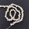 Vue détaillée de perles d'eau douce naturelles avec un éclat crème sur fond noir - 4-5mm / Blanc