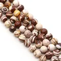 Vista macro di perle tonde in pietra zebra naturale con strisce marroni e beige per gioielli - 4mm