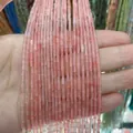 Gros plan de perles cylindriques en pierre naturelle rose tenues pour bijoux DIY - Couleur Quartz Rose / 2x4mm