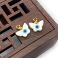 Macro view of butterfly shell pendants with devil's eye design and gold metal loops - Butterfly