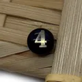 Macro shot of a black round shell bead featuring a metallic silver number 4 for DIY jewelry - Number 4 / Black