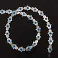 Macro detail of natural mother of pearl Hamsa beads with blue evil eye pattern - Hand Shape / 7x9mm
