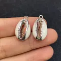 Gros plan de pendentifs en coquillage blanc faits main avec bords en métal argenté - Argent