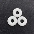 Three white natural stone donut charms for DIY jewelry making on black mesh background - White Jade