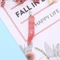 Macro detail of horn-shaped pink natural stone pendant with silver metal bail on a card - Watermelon Quartz