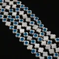 Macro detail of white mother of pearl clover beads with blue evil eye patterns on black background - 8mm / Four-Petal Flower