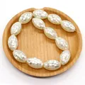 Makroansicht ovaler Perlmuttperlen im Mosaik-Design auf Holztablett für DIY-Schmuck - Weiße Muschel Stil / Weiß