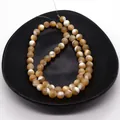 Detailed view of natural shell round beads with brown textures in a black tray for DIY jewelry - 2mm / Natural