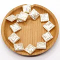 Macro detail of square mother of pearl mosaic beads in a rustic wooden tray - White Shell