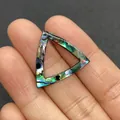 Macro shot of a triangular iridescent abalone shell pendant held by hand for size reference - Triangle Hollow / 22mm