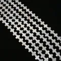 Macro view of white mother of pearl cross beads strands on black background - Cross
